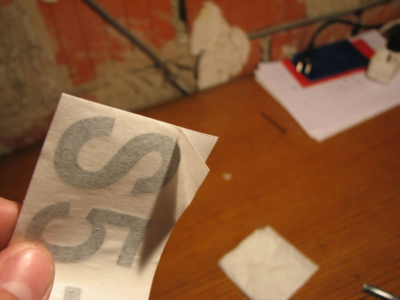 Tukaj se lepo vidi povoskani papir na katerega je nalepljena nalepka (na zadnji strani) in tisti papir, ki ga odstraniš potem, ko je nalepka že nalepljena na model (spredaj). Le-ta prepušča vodo.